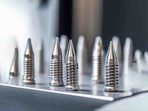 Close-up of custom self-drilling screws with sharp drill-shaped tips and detailed threading, showcased on a professional work surface. The image highlights the screws' ability to drill and fasten metal or wood materials seamlessly, ideal for construction, automotive, and home appliance applications.